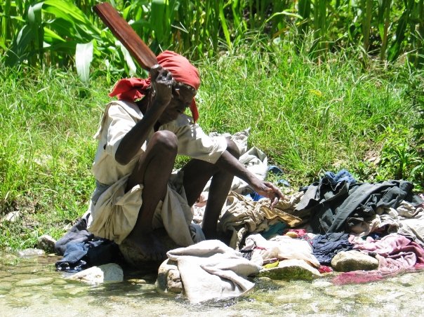 Woman washing clothes in a stream in Haiti